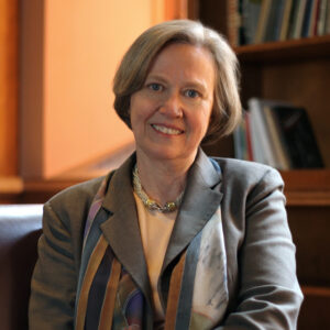 A professional photo of Shirley Tilghman wearing a gray blazer, pale orange shirt, and necklace.